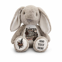 A plush stuffed bunny in warm taupe-gray with long floppy ears, shown against a plain white background. The front has a printed graphic on the belly, and both feet have circular printed areas; one says 'ADD TEXT HERE' and the other shows a tattoo-style dagger illustration.