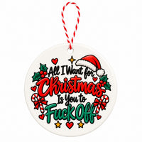 A round white ceramic Christmas ornament with a red and white striped hanging string. The ornament features a festive graphic with the text 'All I Want for Christmas Is You to Fuck Off' in red, green, and black lettering, decorated with a Santa hat, candy canes, holly leaves, and stars.