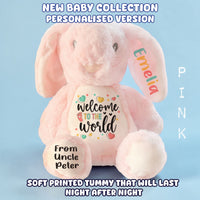 A pink plush bunny toy with custom personalization, featuring a white belly patch that reads 'Welcome to the world' with colorful hearts, a name patch on the ear that says 'Emelia', and a name patch on the foot that says 'From Uncle Peter'. The image has promotional text overlays on a light blue background.